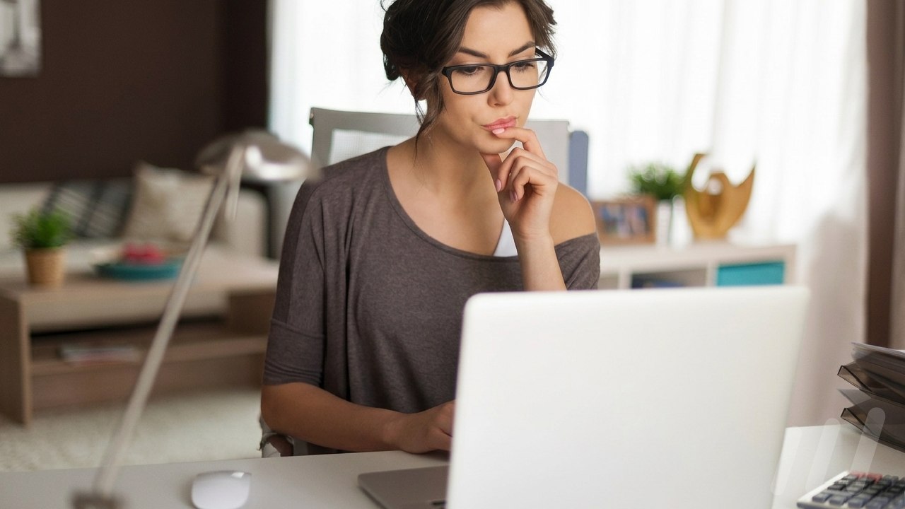 Une personne lisant attentivement un document sur son ordinateur portable
